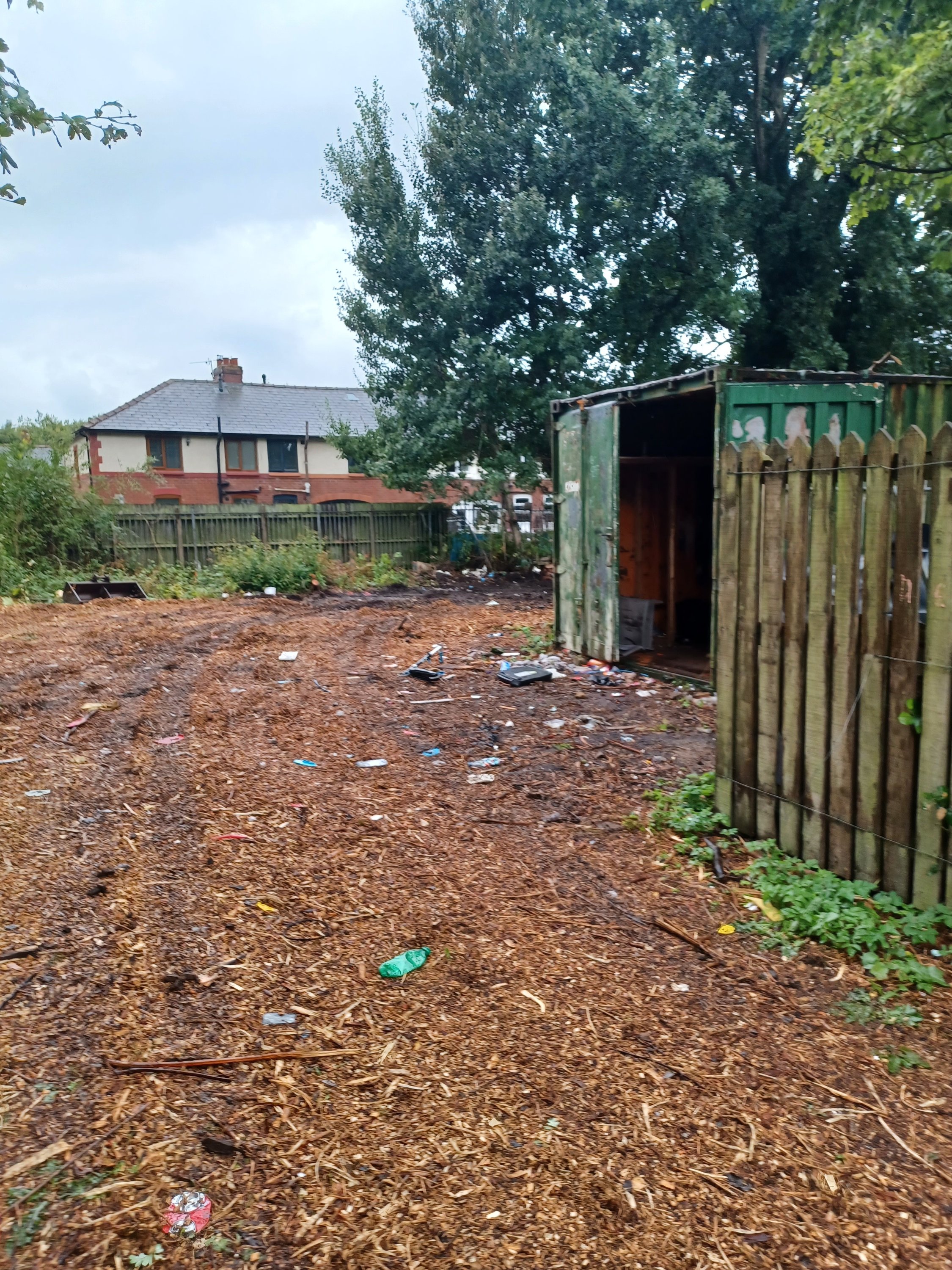 The area before the clean-up project, filled with litter, fly tip and a shipping container. 