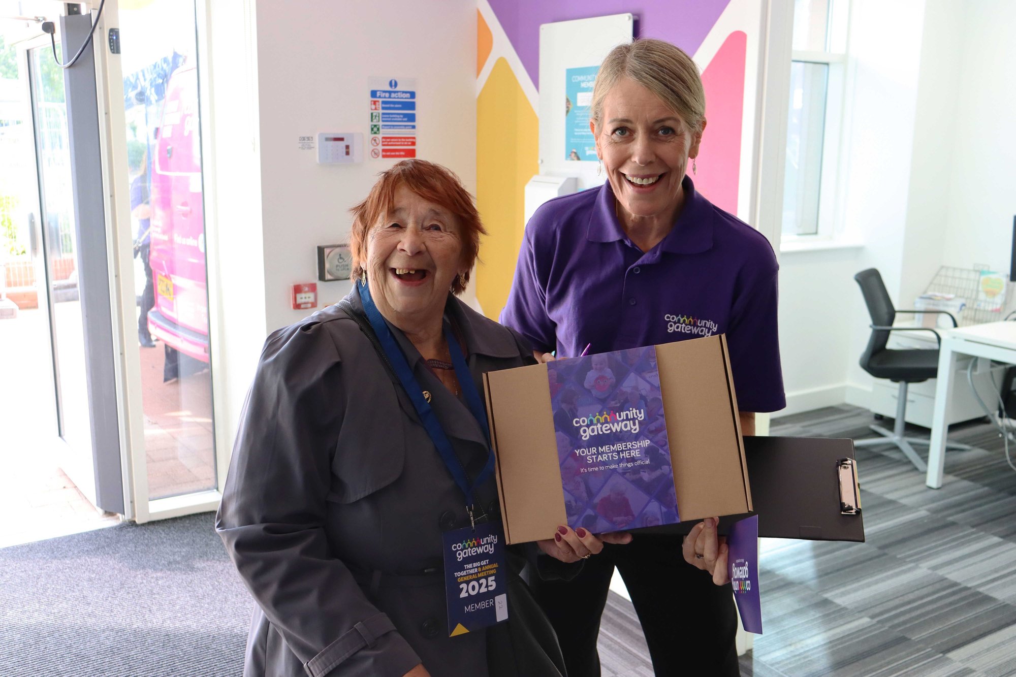CGA colleague stood holding a Membership box with a tenant both smiling at the camera