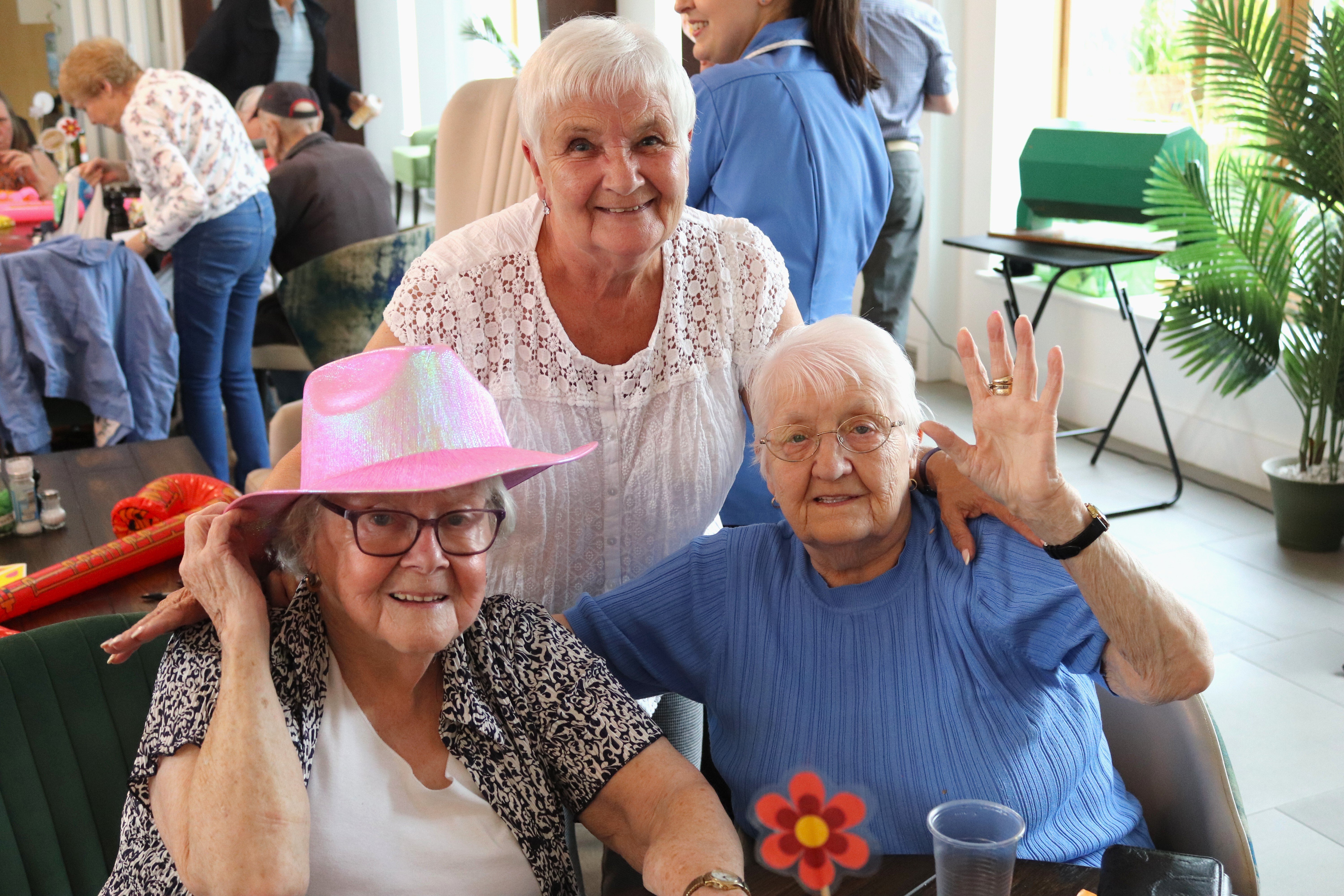 Three older ladies with white hair smiling at the camera