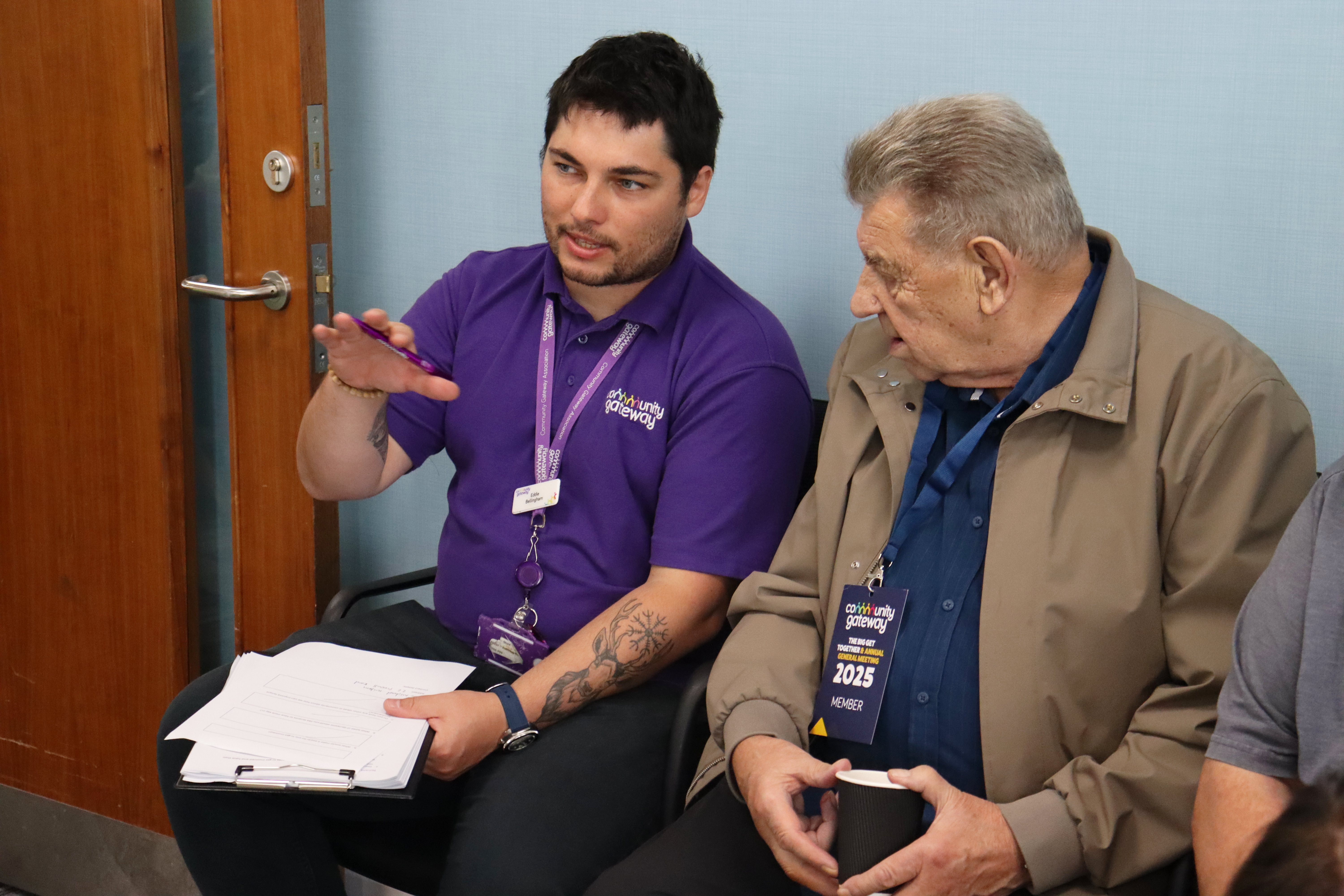 A member of CGA staff with a piece of paper on a clipboard, completing a form with a tenant