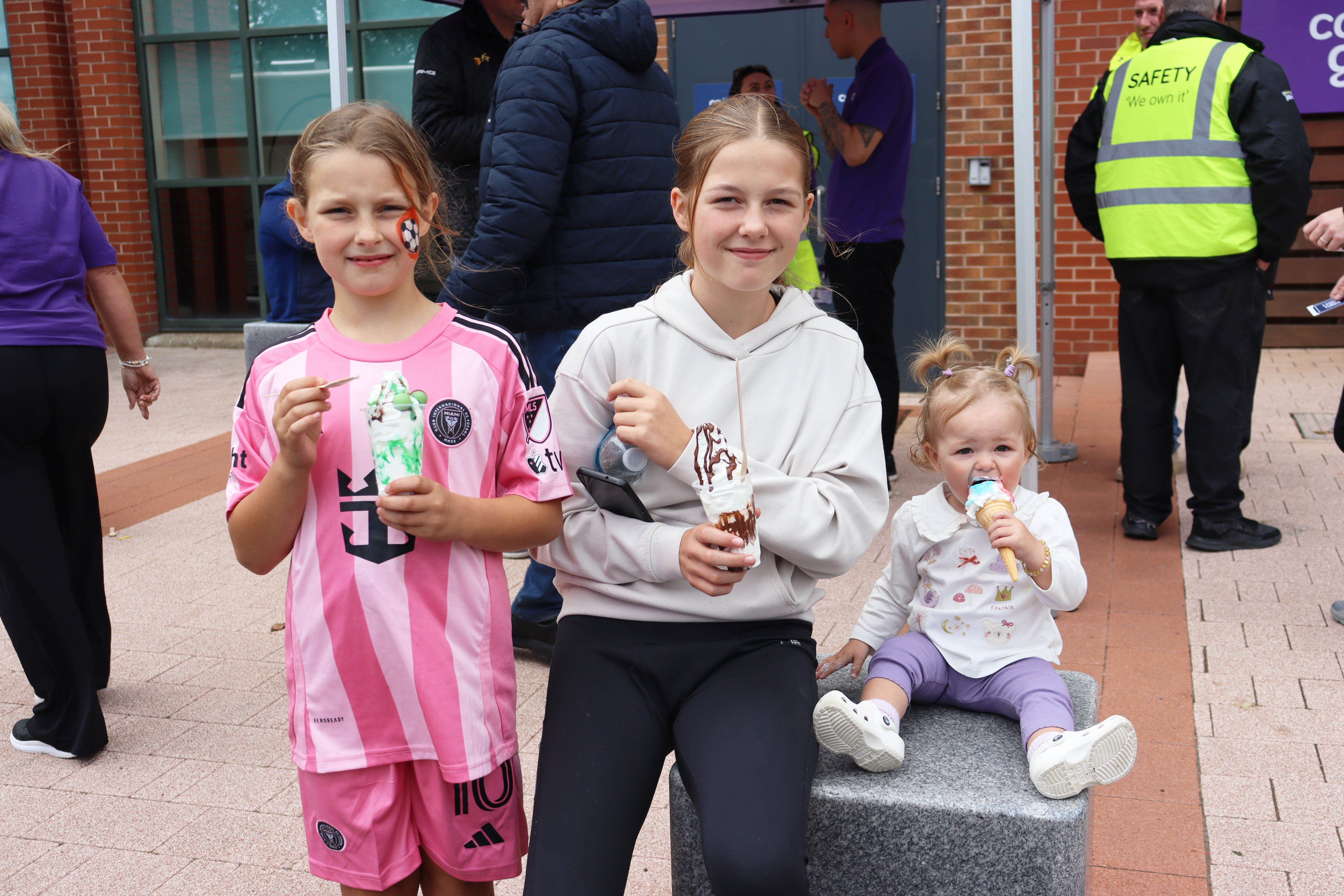 Three young girls eating ice cream smiling at the camera