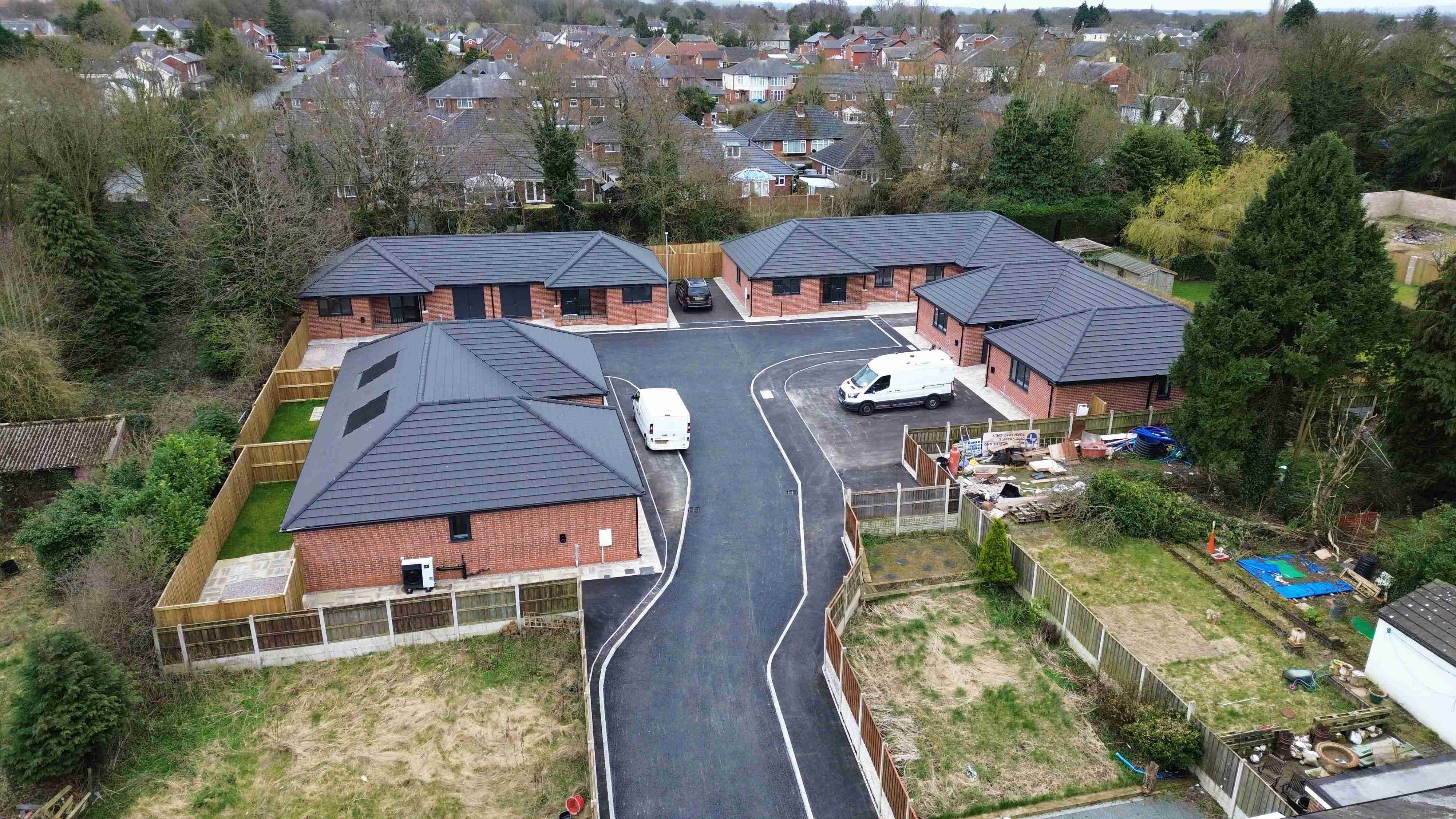 High angle drone shot of 8 red brick bungalows on a new estate