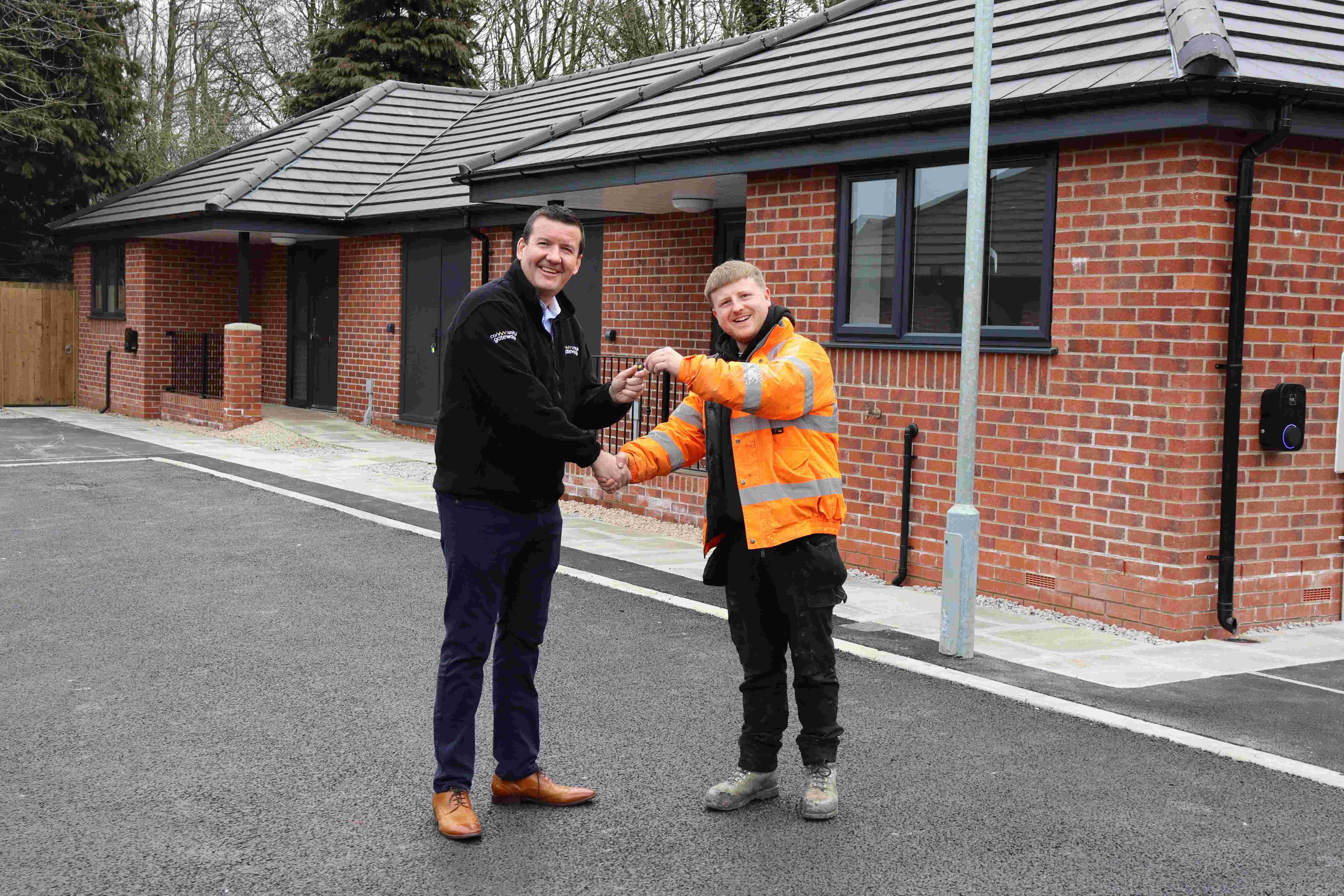Rob Wakefield shaking hands with another person wearing an orange high vis jacket, handing over a set of keys