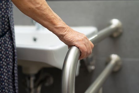 Showing an elderly tenant using a grip rail in a bathroom in a CGA property